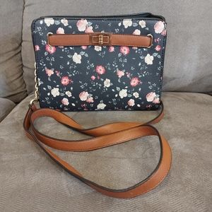 Black crossbody purse with red and white floral pattern and brown strap